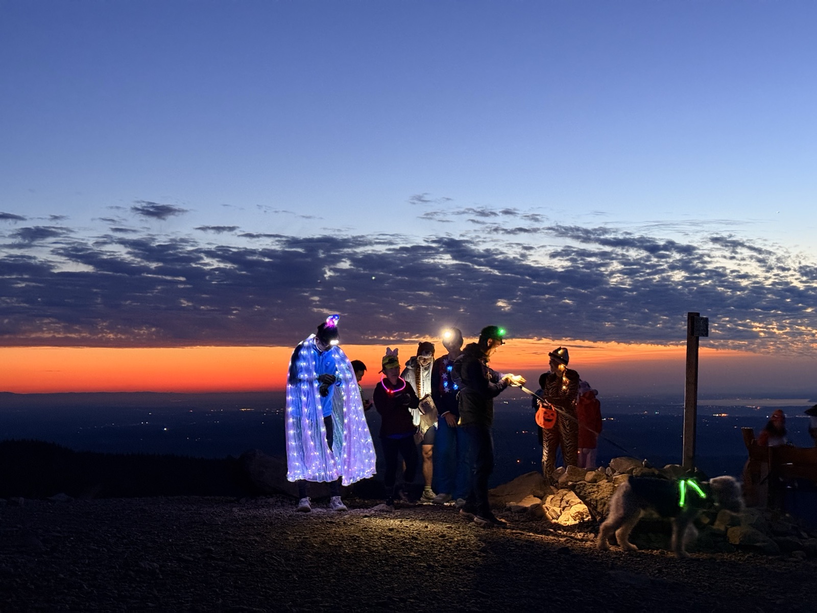 Runners wearing lights together beneath a colorful sunset
